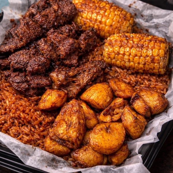 Spicy ribs, corn on the cob, fried plantains, and rice in a black tray lined with parchment paper.