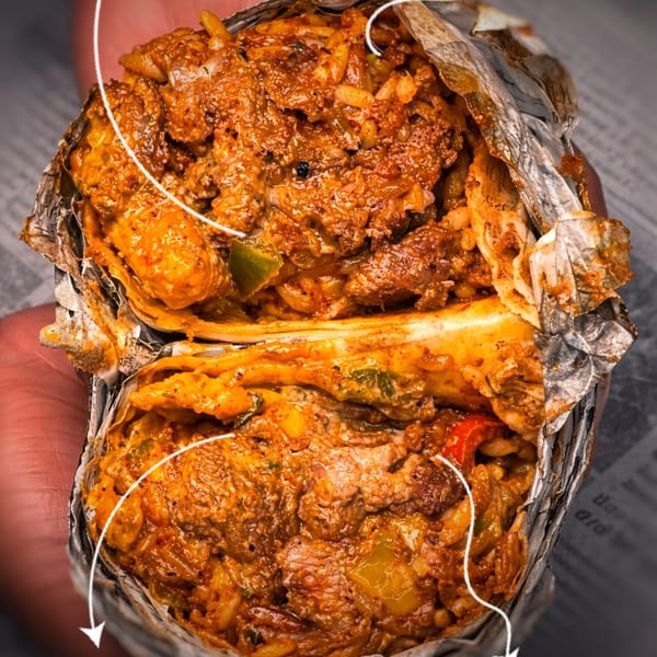 A large, open burrito filled with saucy meat, rice, and vegetables, wrapped in foil.